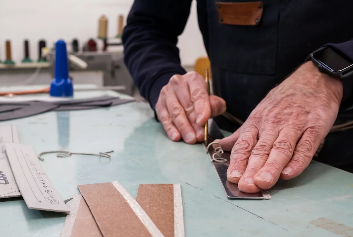 craftsman working on leather components for an Italian leather bag